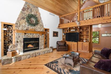 Spacious living room with large stone fireplace, loft in background and smart tv