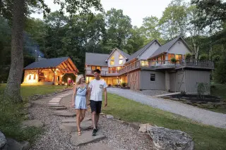 A couple is walking down the stone pathway, stunning cabin and gazebo in the background