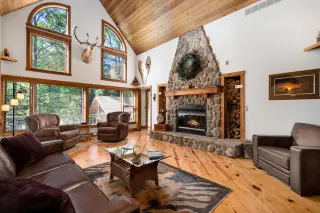 Spacious living room with large stone fireplace, large windows overlooking nature
