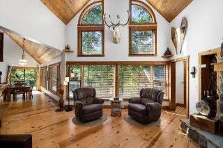 Huge windows in background, overlooking the surrounding nature. 2 recliners in the foreground