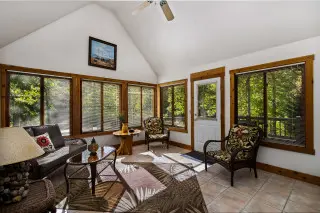 Sunroom, wth windows on all walls, showcasing the greenery surrounding