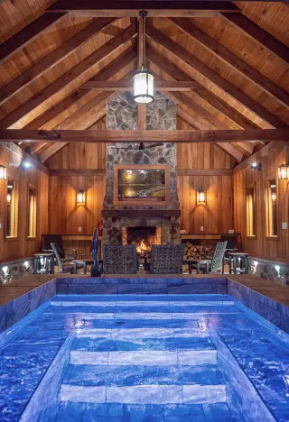 Stone fireplace in background surrounded by seating, with plunge pool in foreground