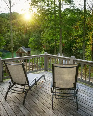 two lounge charis on the wraparound deck, overlooking the lake and surrounding nature