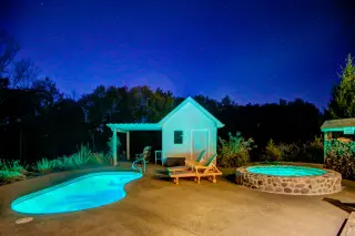 Private pool and cold plunge, lighted with a blue light. Night exterior. 