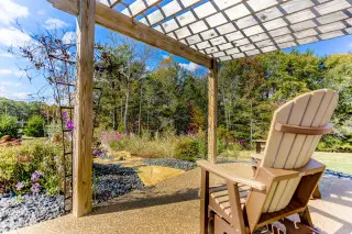 Gliding chair overlooking landscaped views. Flowers growing around, blue skies above. 