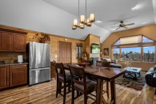 Dining table with living room in the background, fridge and kitchen counter to the side. 