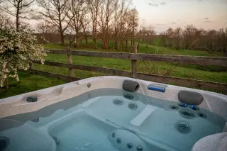 Crystal Clear water in the private, secluded hot tub, with rolling hills and fields in the backgroun. 