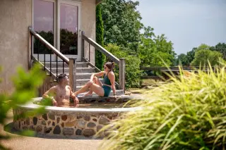 Man sits in a cold plunge, woman relaxes along the rim of the plunge