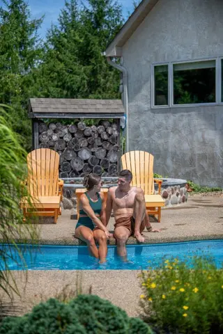 Man and woman sit with their feet in the pool