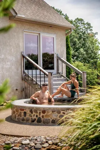 Man sits in a cold plunge, woman relaxes along the rim of the plunge