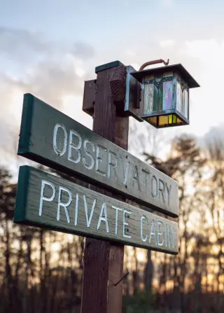 Rustic sign with lantern on top. Sign reads Observatory Private Cabin
