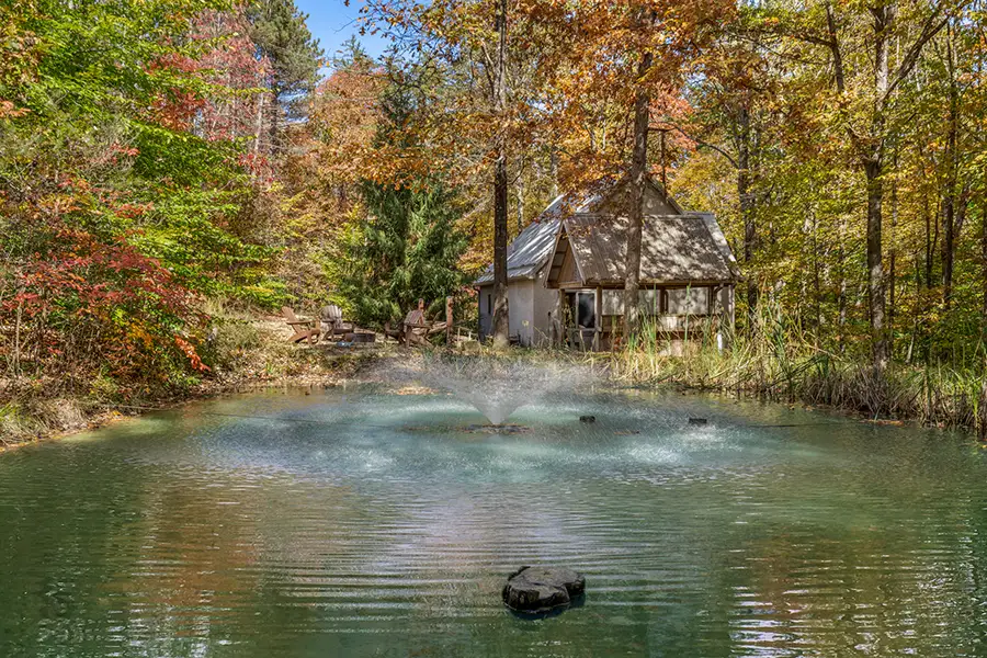 Private pond and illuminated dock surrounded by fall foliage at a Hocking Hills cabin