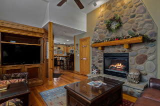 Cabin living room, stone fireplace, flat screen tv, and coffee table. 