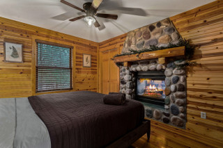Bedroom with stone fireplace, king bed. 