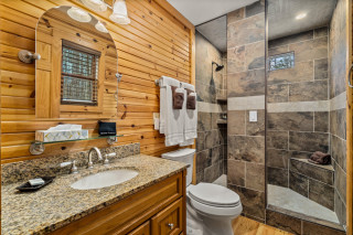 bathroom with tile shower, toilet and sink