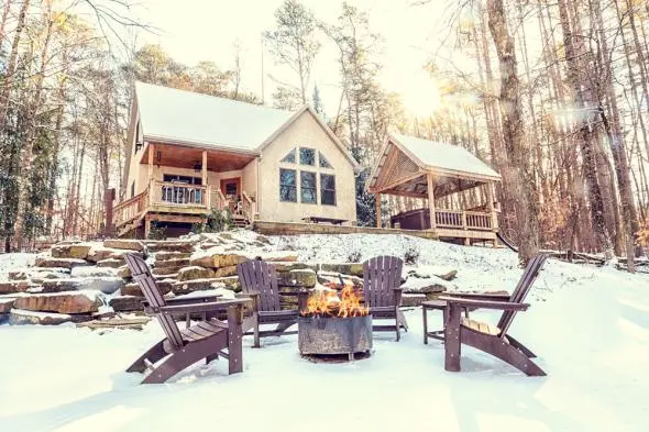 Still waters cabin situated in secluded woods, stone steps lead up to cabin. Fresh coat of snow on the ground