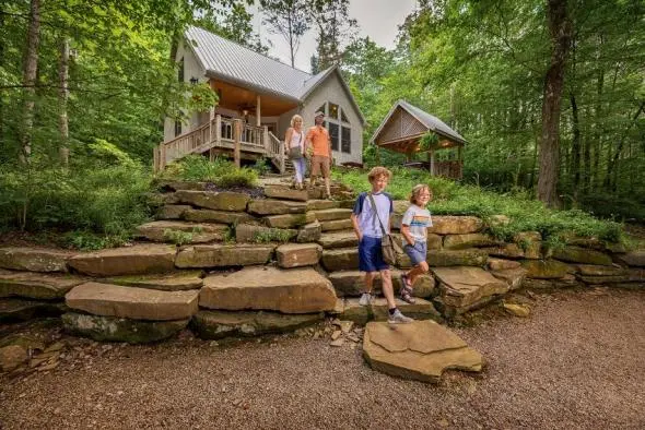 A family going down the stone steps of our Still Waters luxury cabin. Greenery surrounding.