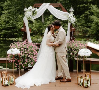 Bride and groom facing one another, officiant in the background, reading the vows
