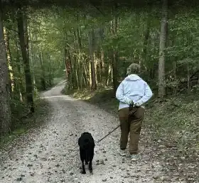 Woman walking down gravel driveway with a dog