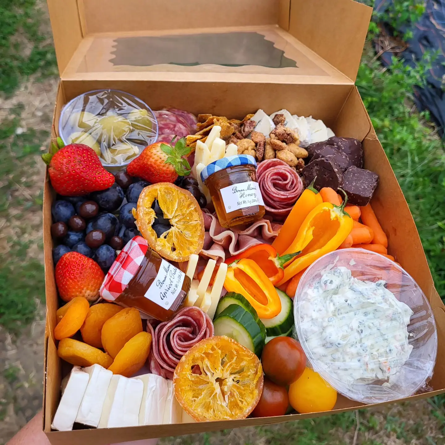 Photo of a medium sized Charcuterie box with meats, fruit, crackers and cheese