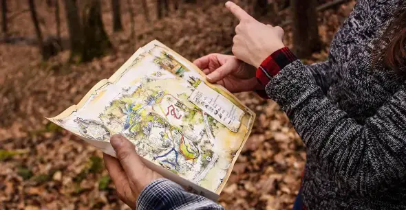 Hands holding a hiking trail map in the forest
