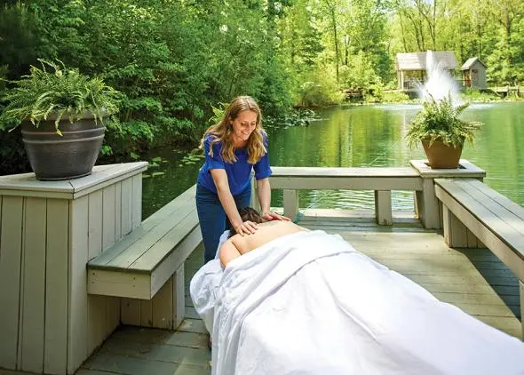 Massage therapist giving a massage, with scenic lake and fountain in background