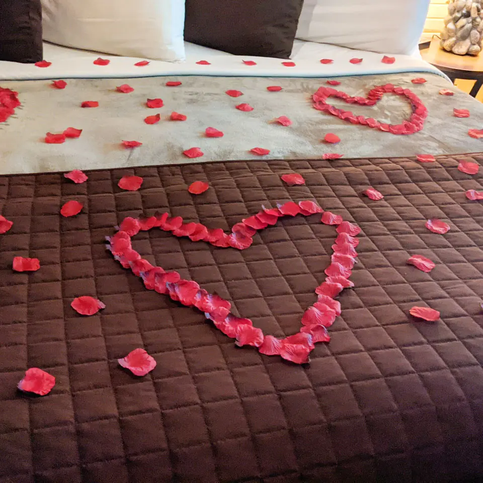 rose petal heart arrangement on a bed