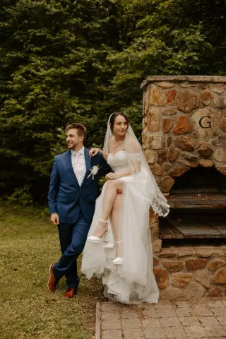 Bride sitting on the edge of a grill, groom stands alongside