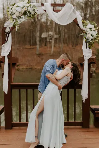 Groom dips his bride in a passionate embrace in front of the decorated archway