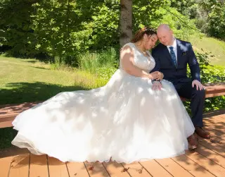 Bride and groom seated under a shady tree