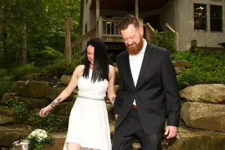 Bride and Groom walking down the stone walkway, cabin in the background