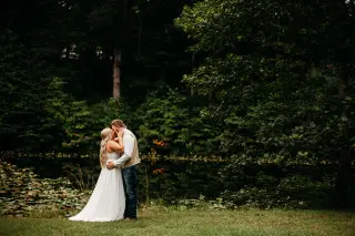 Bride and Groom standing in front of a lake, scenic forest in the background