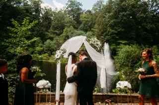 Bride and groom in front of decorated archway, family alongside.