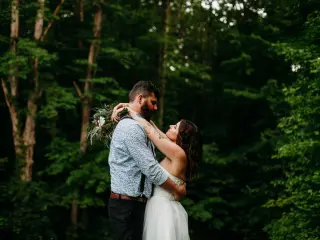 Brode and groom embracing, forest in background