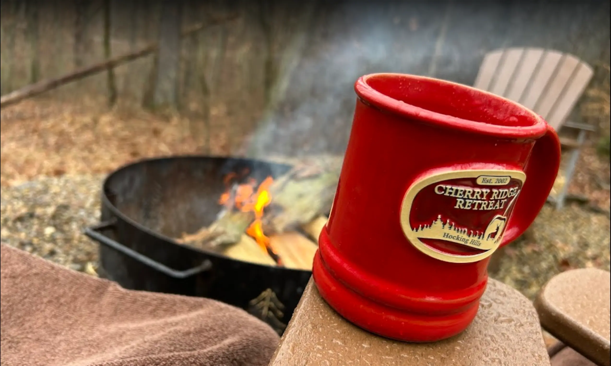 Campfire in background, Cherry Ridge Retreat mug in the foreground