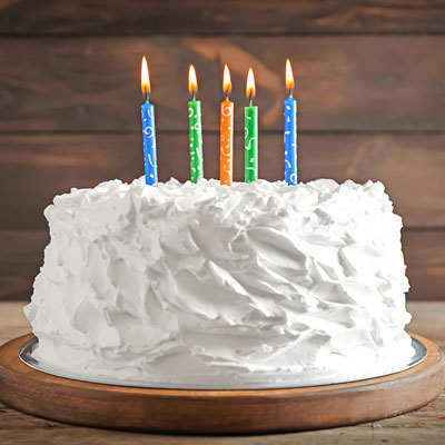 Photo of a white cake with 5 colorful candles