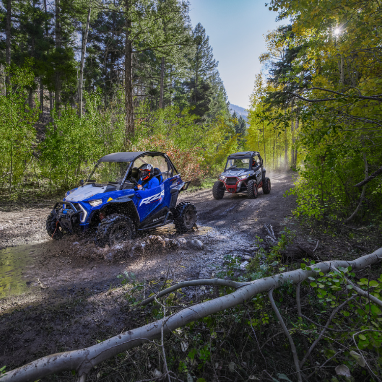 UTVs driving on a muddy off road trail