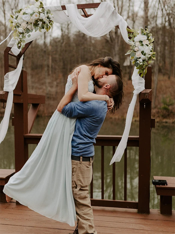 Eloping bride and groom Bride bring picked up and kissed by groom, in front of a decorated archway