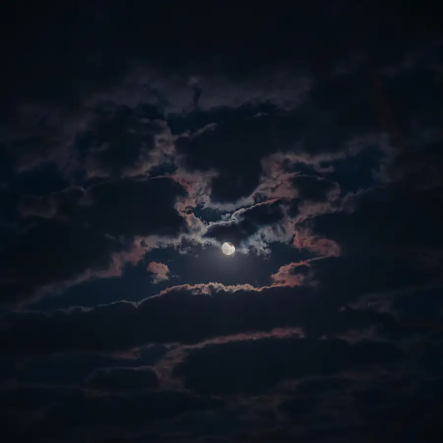 Moon Shining Through Night Clouds Bright moon shining through dramatic dark clouds in the night sky.