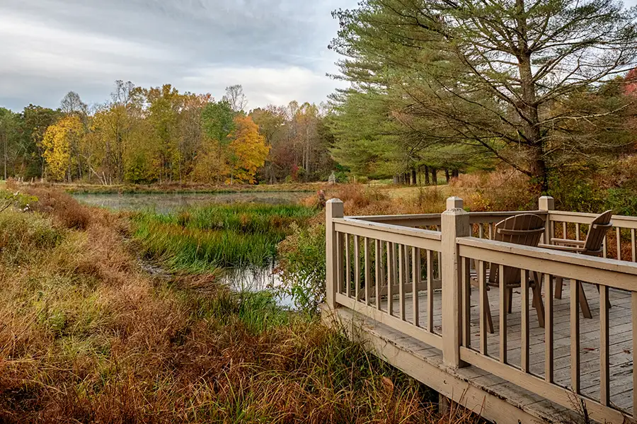 Wooden viewing deck overlooking a peaceful pond and fall landscape