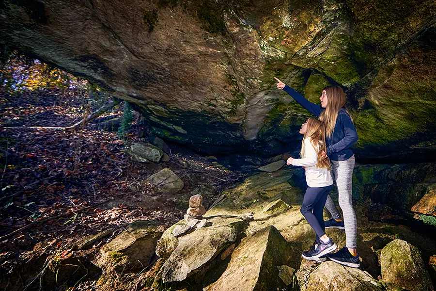 Sisters exploring a natural rock shelter in Hocking Hills 