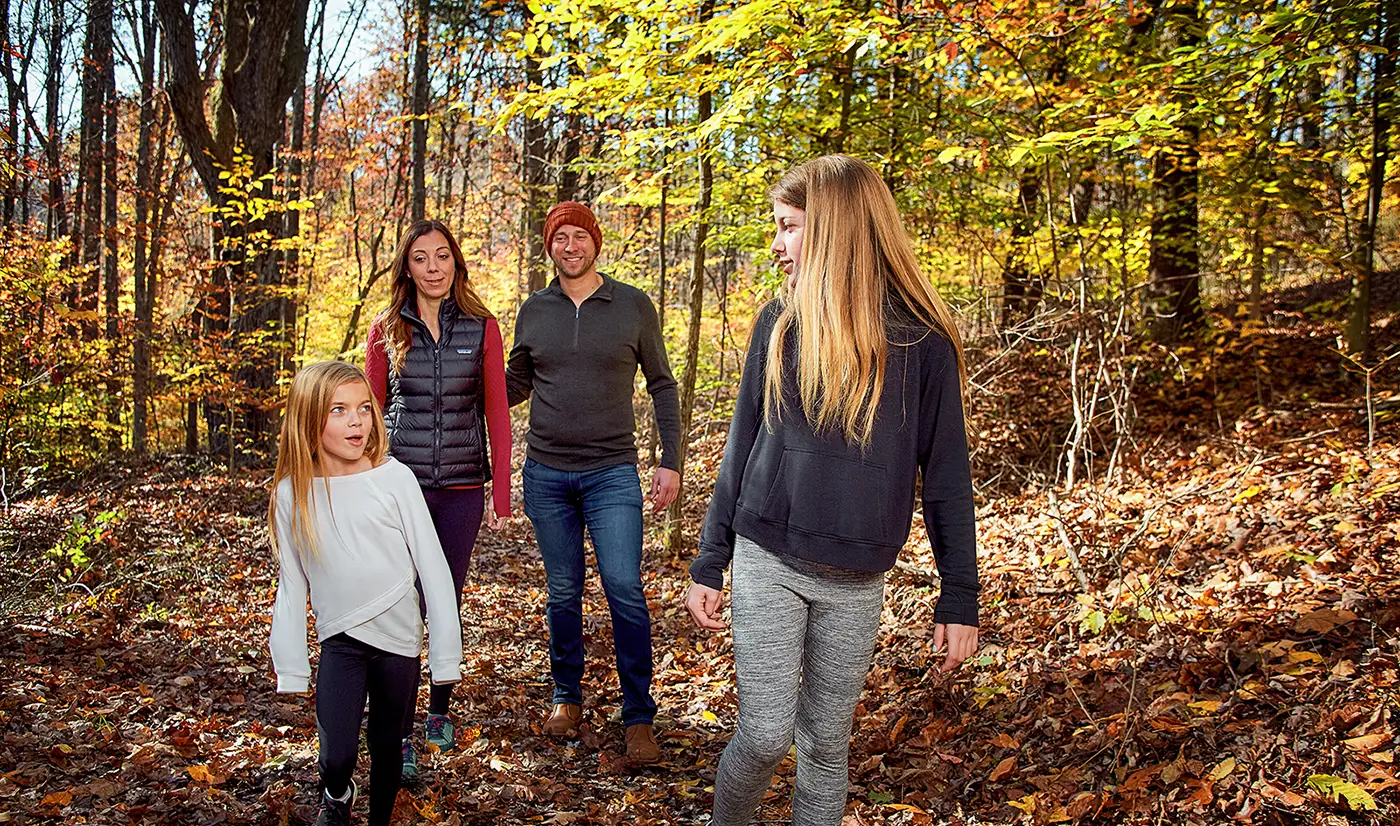 Family hiking together on a wooded trail during fall in the Hocking Hills