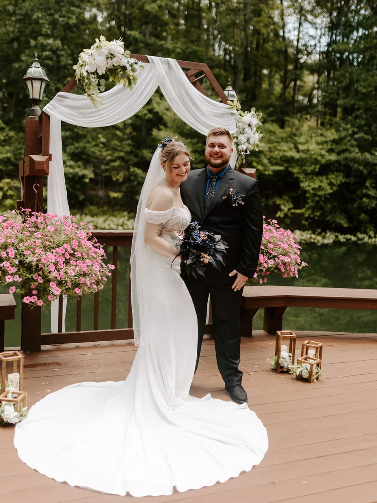 Bride and groom stand before a decorated wedding archway