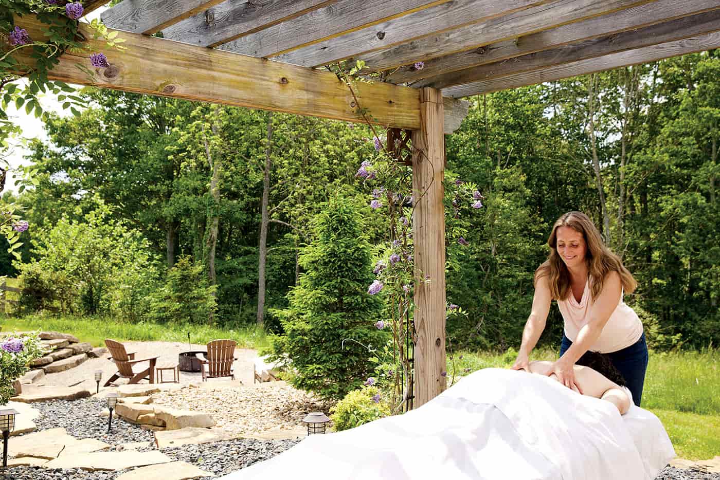 Massage Therapist massaging a guest outdoors, scenic views in background