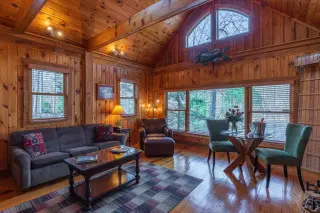Spacious wooden living room. Large windows overlook the scenic beauty outside