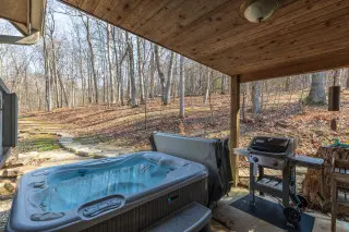 Bubbling hot tub, with gas grill nearby, forest in the background