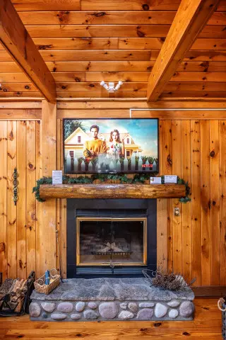 TV mounted above fireplace in wooden cabin interior