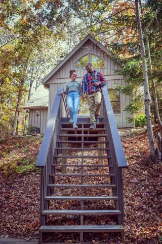 Man and woman walking down wooden steps, cabin in background