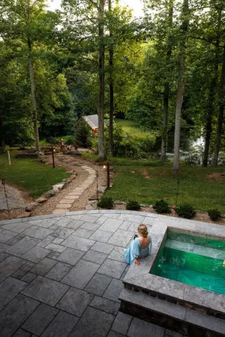 A woman sits on the bench ledge of the plunge pool, overlooking the views