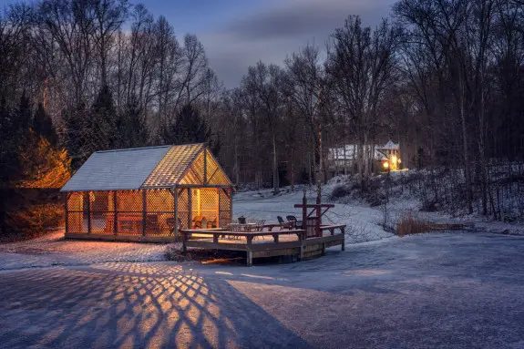 A gazebo glowing in the dusk with warm light, snowy dusting on the ground